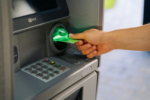 Close-up,Of,A,Persons,Hand,Inserting,A,Green,Bank,Card